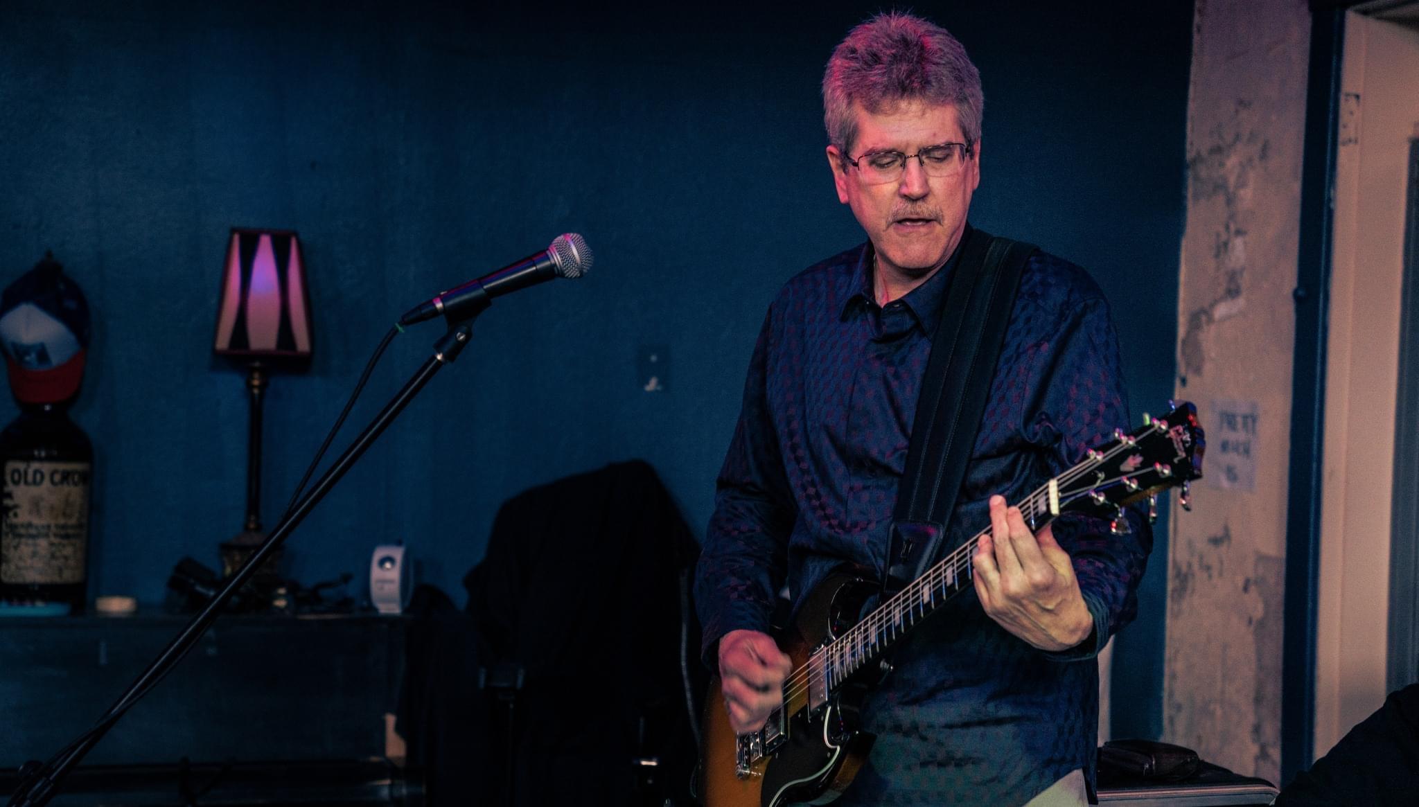 3 Wire Monkey guitarist playing on a dim blues club stage